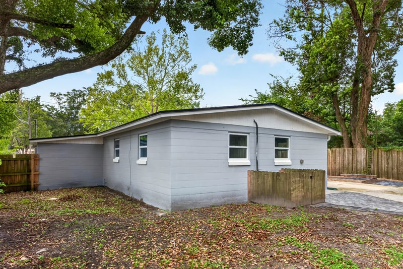 Rear exterior view with trees and yard at 7015 Miss Muffet Ln N, Jacksonville, FL 32210