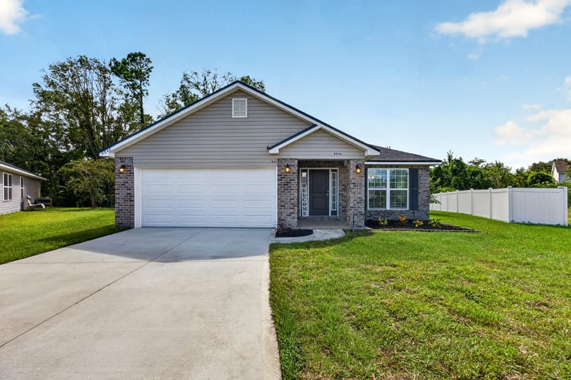 Front exterior with two-car garage and green lawn at 9846 Olivia St, Jacksonville, FL