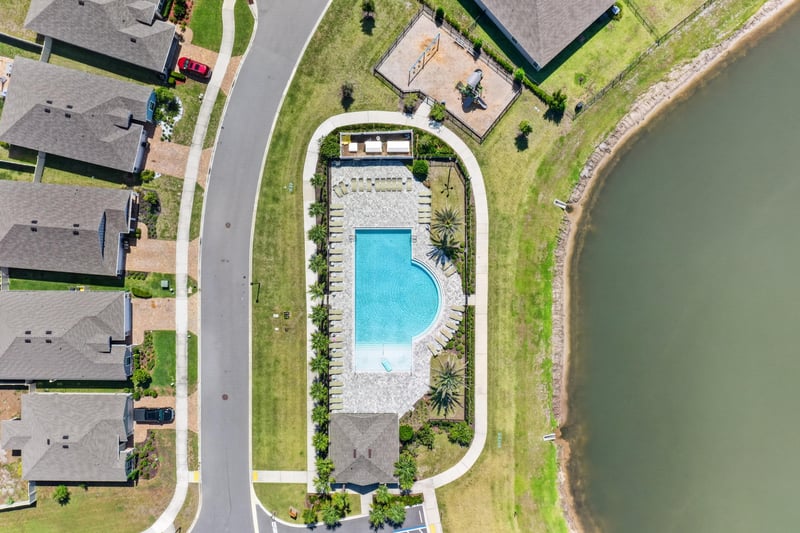 Drone view of community pool and lake in Highland Chase