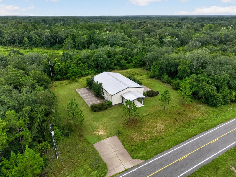 Drone aerial of the building and gravel driveway in the trees at 1038 County Rd 315, Melrose