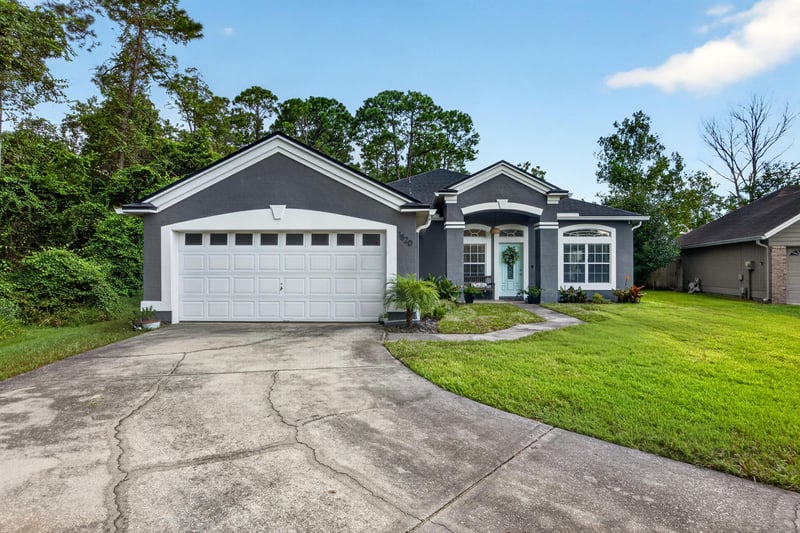 Front exterior with two-car garage and lawn at 1820 Burgess Hill Dr E, Jacksonville, FL