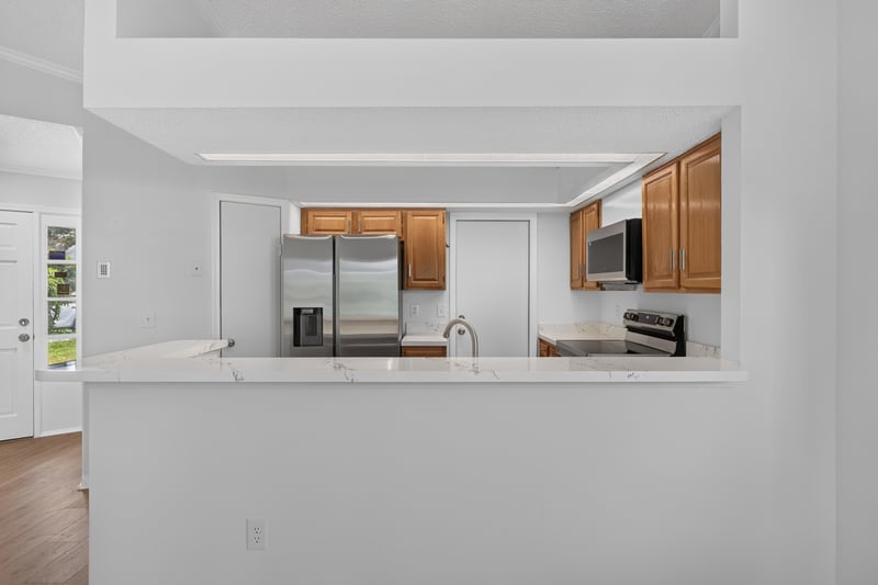 Kitchen pass-through with wood cabinets and stainless appliances at 8047 Mactavish Way E, Jacksonville, FL 32244