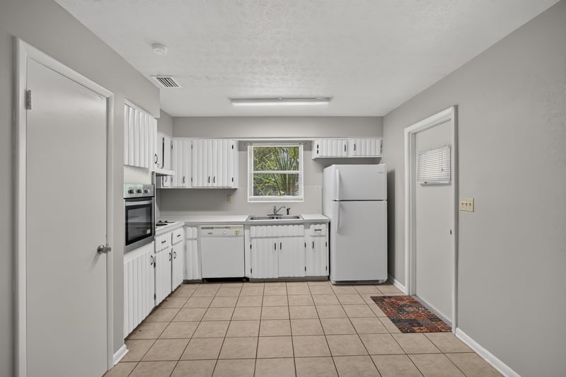 Kitchen with white cabinets, tile floor and window over sink at 5527 Beney Rd, Jacksonville, FL 32207
