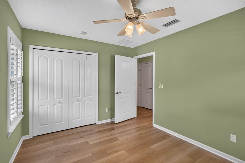 Bedroom corner with plantation shutters and wood floors at 2131 E Stone Creek Dr, Fleming Island, FL