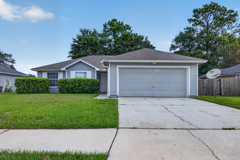 Front exterior with white garage door and lawn at 8519 Blazing Star Ct, Jacksonville, FL 32210