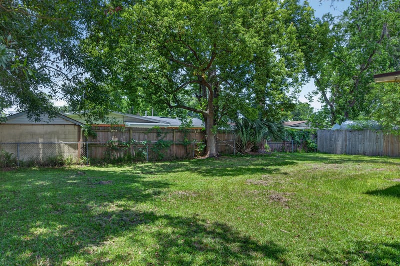 Backyard with mature trees and open grass at 5527 Beney Rd, Jacksonville, FL 32207