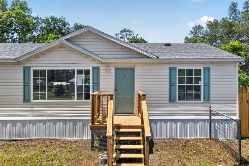 Front exterior with teal door and wood steps at 7603 Coach Park Dr, Jacksonville, FL 32244