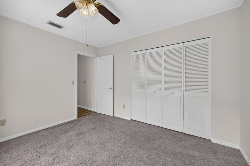Carpeted bedroom with louvered closet doors at 3407 Fairbanks Grant Rd N, Jacksonville, FL 32223