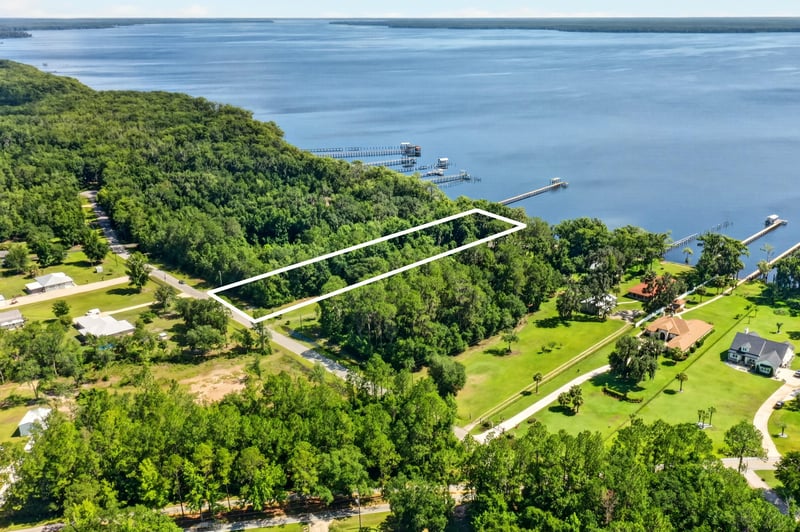 Aerial view of the wooded lot with white boundary outline along the river at 110 River Shores Rd, Palatka, FL 32043