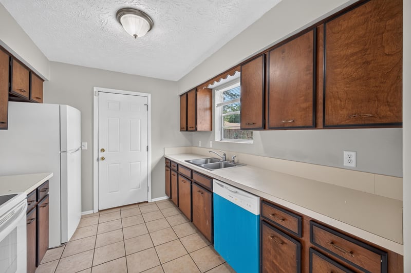 Kitchen sink area with tile backsplash and wood cabinets at 1083 Stokes St, Jacksonville, FL
