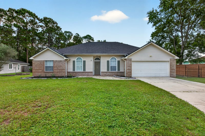 Brick ranch front exterior with two-car garage and lawn at 8921 Needlepoint Pl, Jacksonville, FL 32244