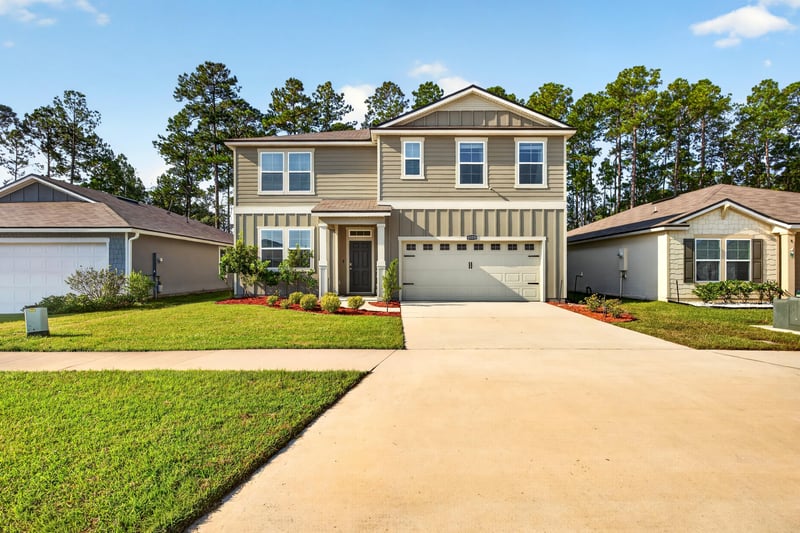 Front exterior with two-car garage and landscaped lawn at 65255 Frst Glen Ln, Yulee, FL 32097