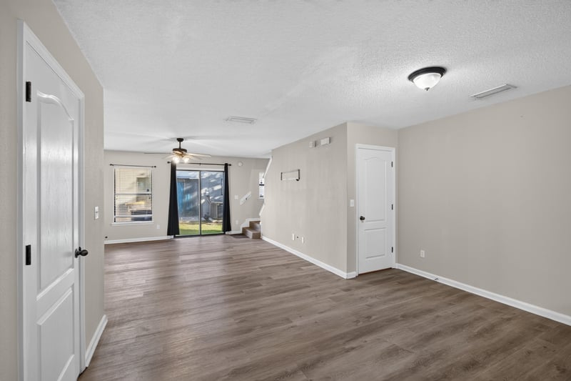 Empty living room with wood-look flooring and sliding glass door at 7723 Playschool Ln, Jacksonville, FL