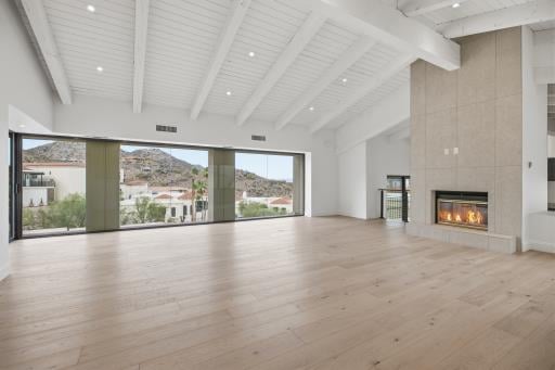 Great room with a beamed ceiling and fireplace, empty