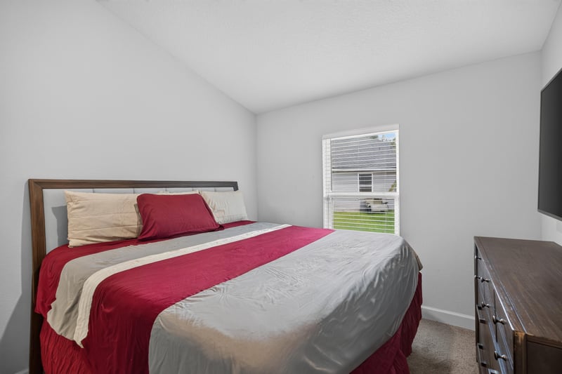 Bedroom with red bedspread and nightstand at 9846 Olivia St, Jacksonville, FL