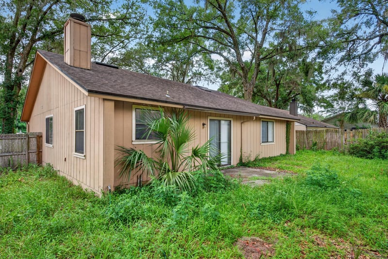 Rear exterior with chimney and open yard at 1445 Classic Oak Rd W, Jacksonville, FL