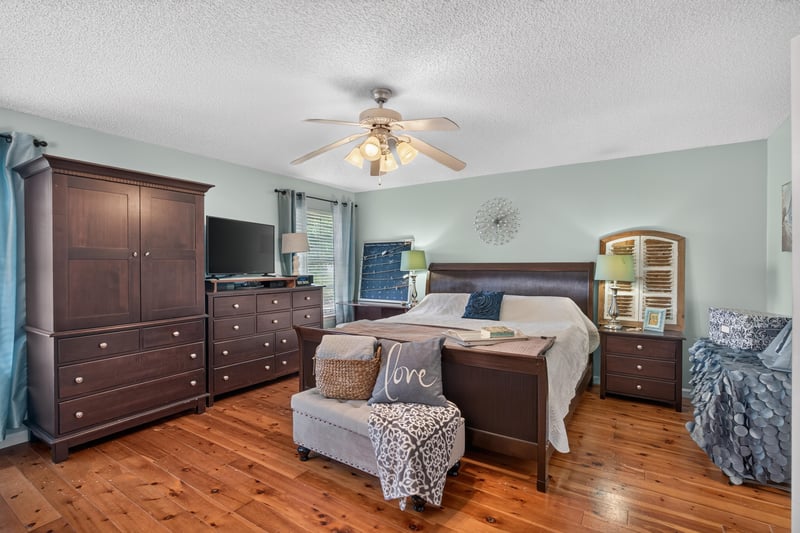 Primary bedroom with dark wood furniture and TV at 4556 Shaky Leaf Ln N, Jacksonville, FL 32224