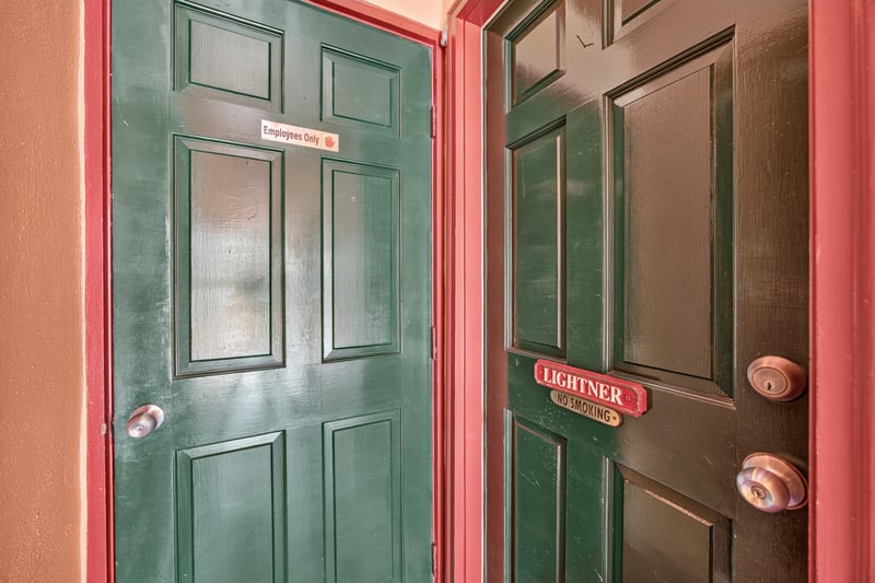 Hallway with green doors and room nameplates at 115 Cordova St, St. Augustine, FL