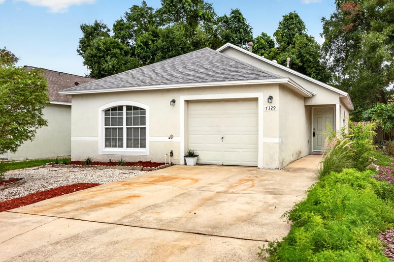 Front exterior with two-car garage and concrete driveway at 7329 Lawn Tennis Ln, Jacksonville, FL