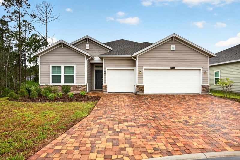 Front exterior with paver driveway and three-car garage at 9905 Ansley Lake Dr, Jacksonville, FL