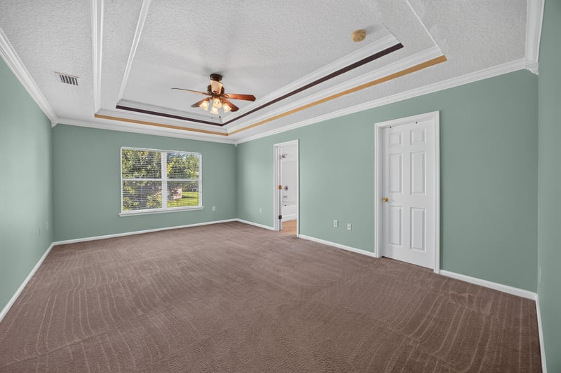 Empty primary bedroom with tray ceiling and carpet at 2282 Justin Lake Dr, Jacksonville, FL