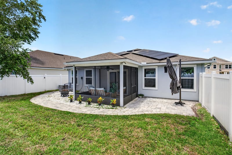 Backyard view of the home with solar roof panels at 10066 Andean Fox Dr, Jacksonville, FL 32222