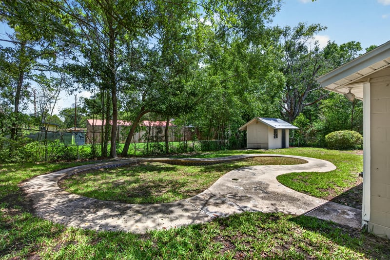 Backyard view with mature trees and winding path at 7453 Jade Dr N, Jacksonville, FL 32210