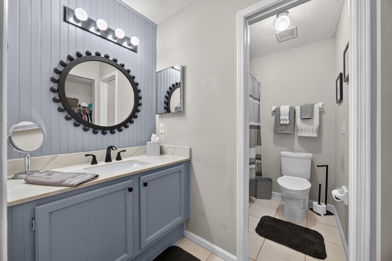Bathroom with round mirror and gray vanity at 3067 Wavering Ln, Middleburg, FL 32068