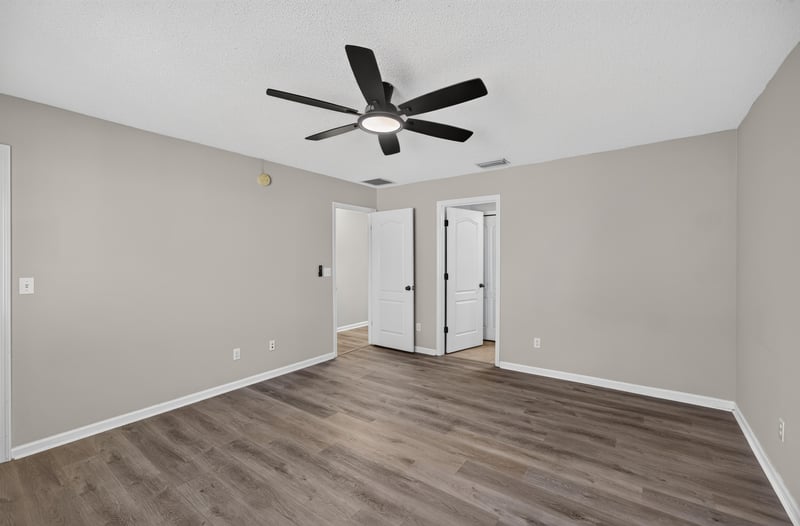 Empty room with wood-look flooring and multiple doors at 7723 Playschool Ln, Jacksonville, FL