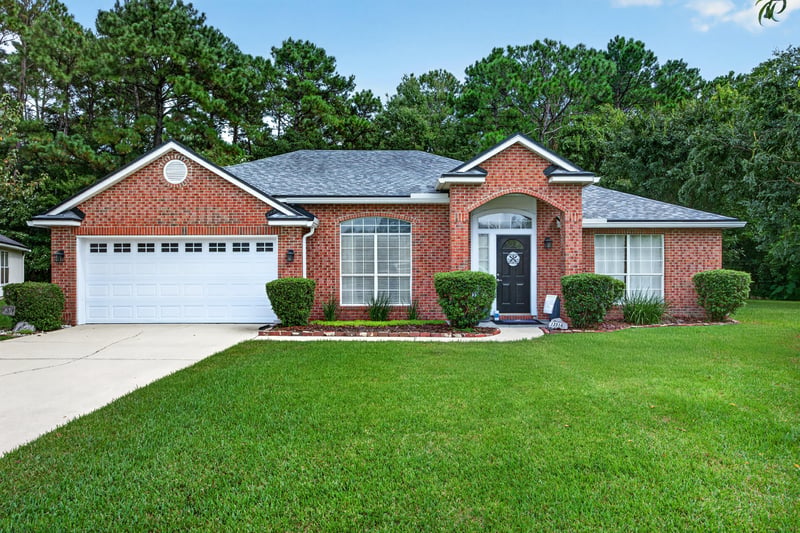 Front exterior straight-on, white garage doors and landscaped lawn at 13514 Las Brisas Way N, Jacksonville, FL