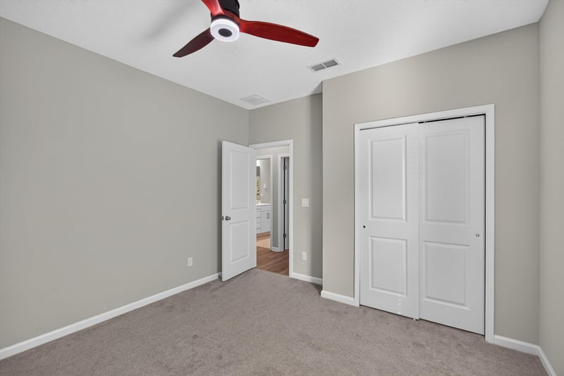 Carpeted bedroom with closet door and ceiling fan at 75875 Saffron Ln, Yulee, FL 32097