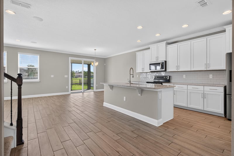 Kitchen with island, wood-look floor and stair railing at 2580 Cold Stream Ln, Green Cove Springs, FL 32043