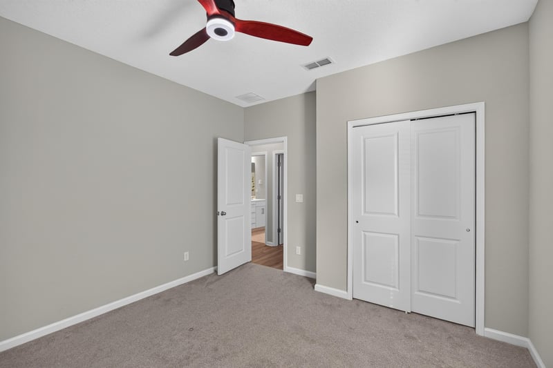 Carpeted bedroom with closet doors and ceiling fan at 75875 Saffron Ln, Yulee, FL 32097