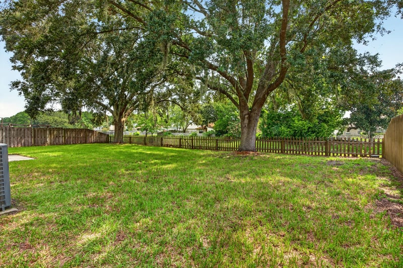 Backyard with open lawn and mature oak trees at 456 Bay Point Way N, Jacksonville, FL 32259