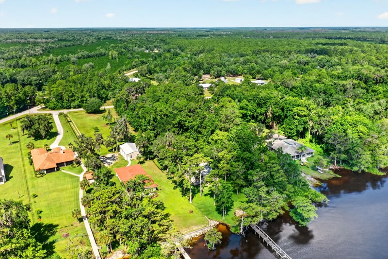 Aerial view of a red-roofed home and dock along the river at 110 River Shores Rd, Palatka, FL 32043