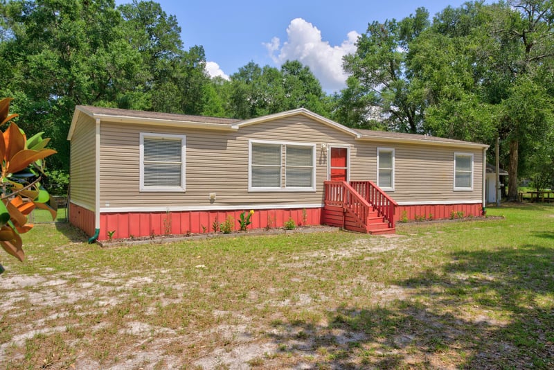 Front exterior with wooded lot and tan siding at 2549 Snapdragon Ave, Middleburg, FL 32068