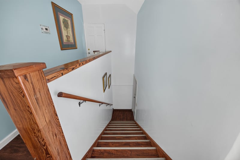 Interior staircase with a wood railing at 115 Cordova St, St. Augustine, FL