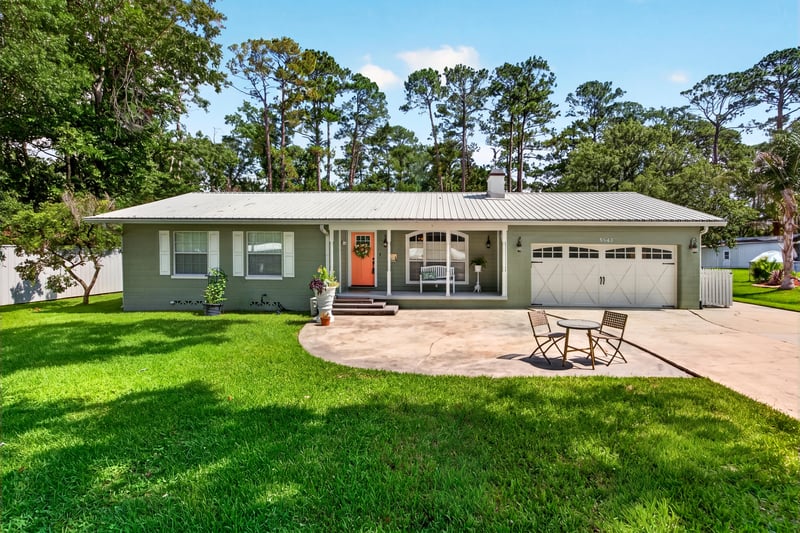 Front exterior across the lawn with mature trees at 5843 Ovella Rd, Jacksonville, FL 32244