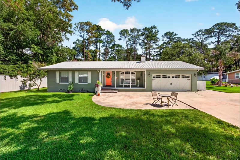 Front exterior with green siding, metal roof, and wraparound driveway at 5843 Ovella Rd, Jacksonville, FL 32244