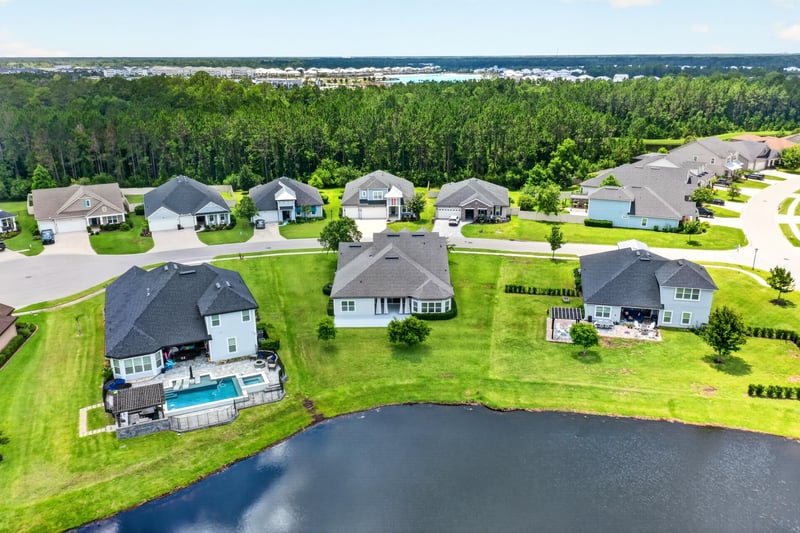 Aerial view of a neighborhood pool home and pond in St. Augustine, FL