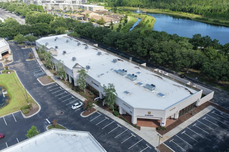 Aerial view of a building roofline with pond and parking at 10550 Deerwood Park Blvd, Jacksonville, FL 32256