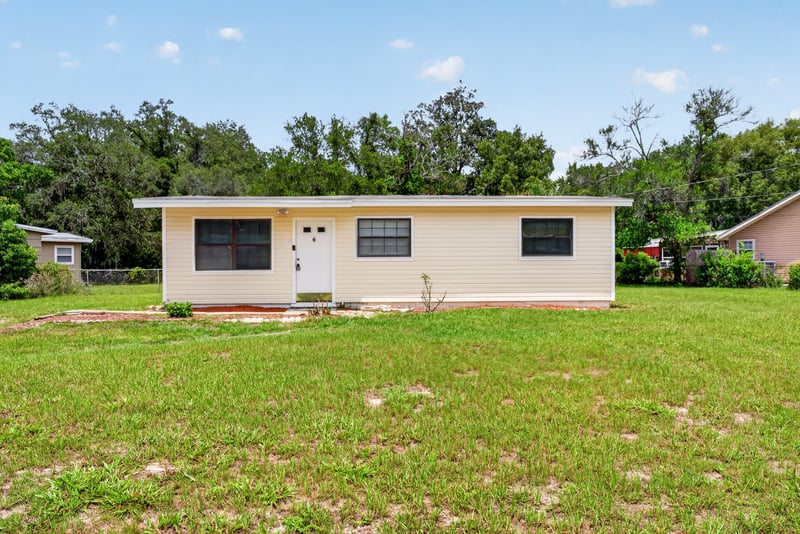 Front exterior with grassy yard and mature trees at 255 Woodside Dr, Orange Park, FL 32073