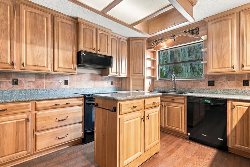 Kitchen island with granite counter and wood cabinets at 2915 Trenton Ct, Orange Park, FL