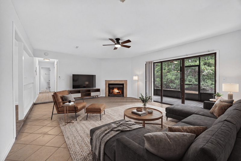Living room with fireplace and sliding glass doors, virtually staged, at 3801 Crown Point Rd unit 2061, Jacksonville, FL 32257