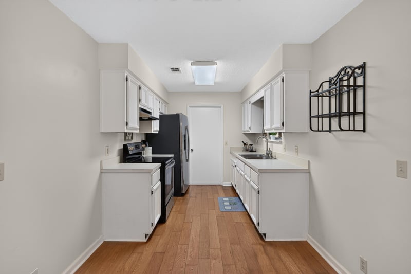 Galley kitchen with white cabinets and wood floors at 2829 Blackberry Ave