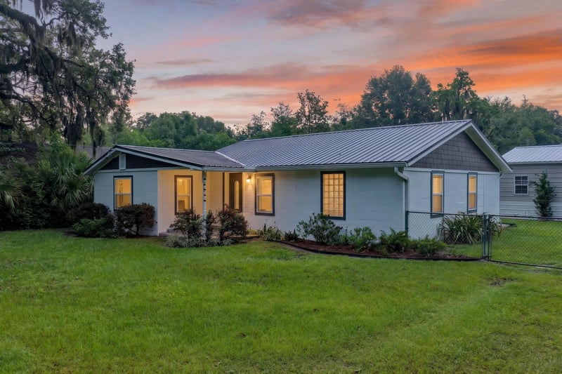 Front exterior at day-to-dusk with metal roof and lit windows at 1619 Hammond Blvd, Jacksonville, FL