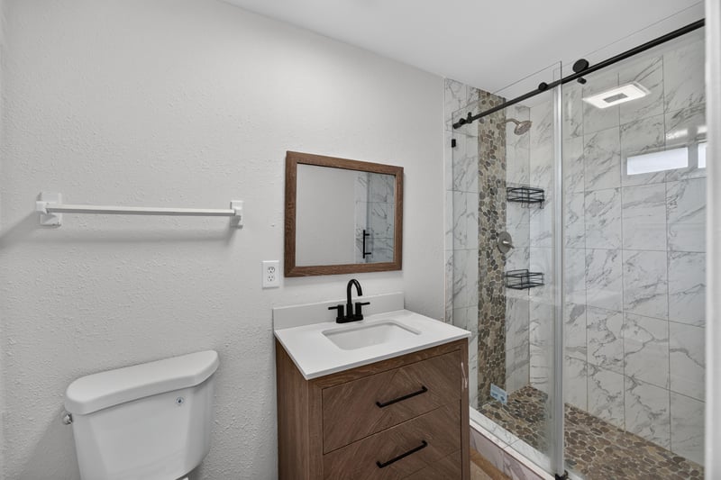 Bathroom with walk-in glass shower and wood vanity at 7453 Jade Dr N, Jacksonville, FL 32210
