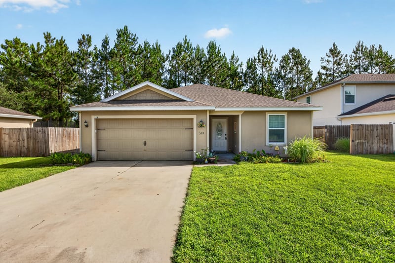 Front exterior with two-car garage and long driveway at 518 Matecumbe Ct, Macclenny, FL