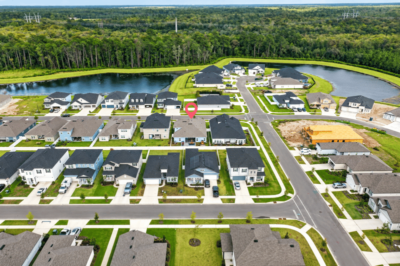 Aerial view of the neighborhood with a pond and new construction in Middleburg, FL