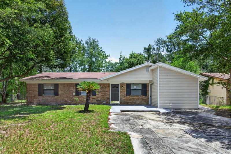 Front entry view with brick accents and landscaped lawn at 7453 Jade Dr N, Jacksonville, FL 32210